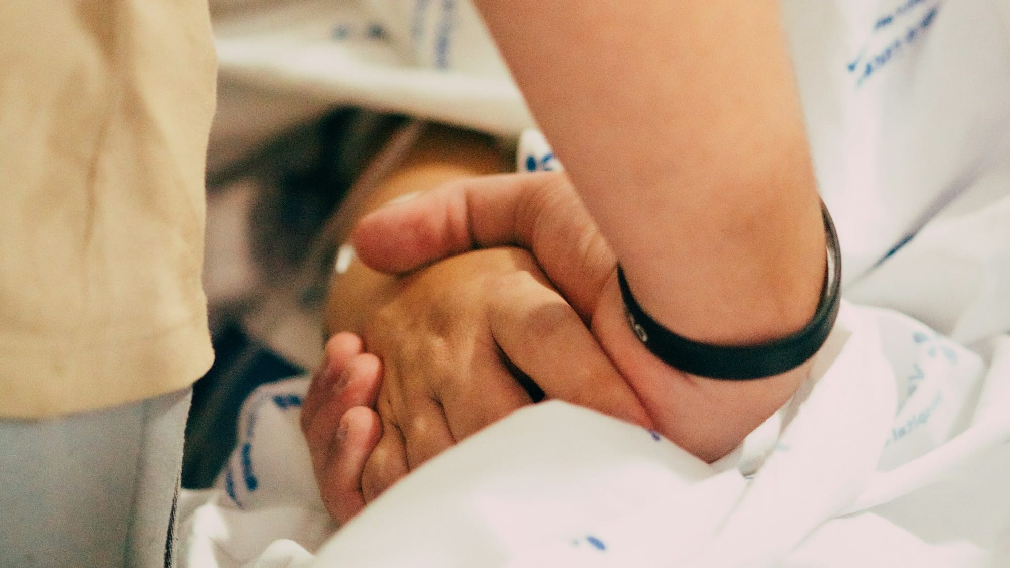 A hand holds another's for comfort